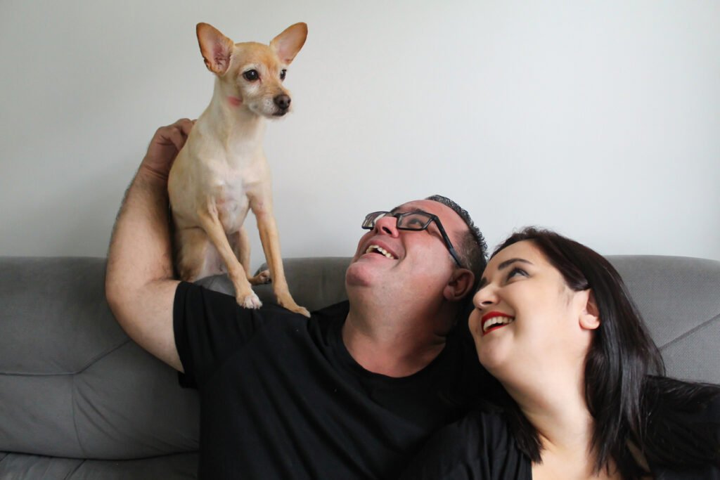 Ensaio fotográfico pet, donos olhando para cachorro no sofá