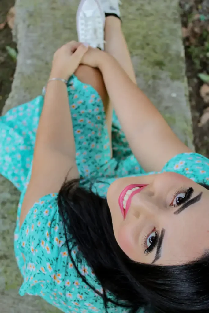 Mulher sentada em uma superfície de cimento, capturada de cima, com expressão suave e cabelos esparramados. Ensaio fotográfico casual com composição criativa e foco na naturalidade.
